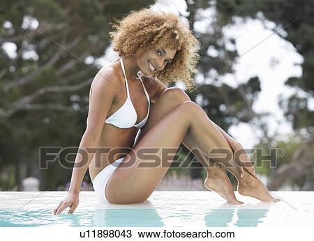 Stock Image - A young woman sitting by a pool. Fotosearch