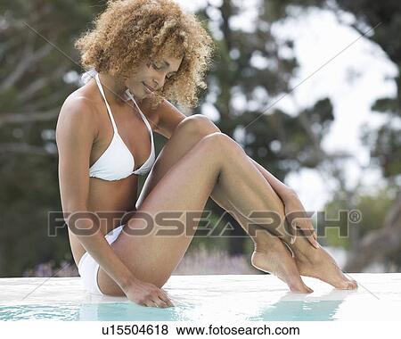 A young woman sitting by a pool View Large Photo Image Stock Photo - A young woman sitting by a pool. Fotosearch