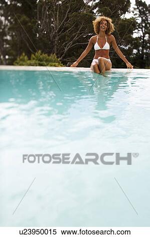 Stock Photography - A young woman sitting by a pool. Fotosearch