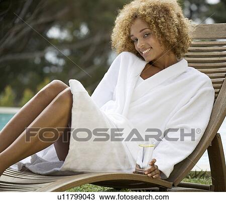 A young woman sitting on a sun lounger View Large Photo Image Stock Image - A young woman sitting on a sun lounger. Fotosearch