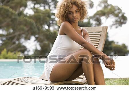 Stock Image - A young woman sitting on a sun lounger. Fotosearch