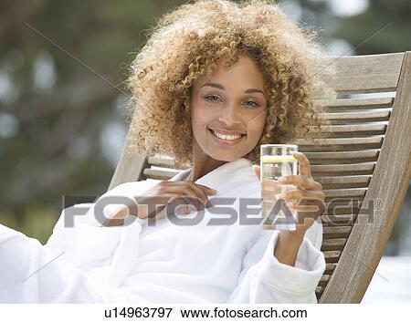 Stock Photo - A young woman sitting on a sun lounger. Fotosearch
