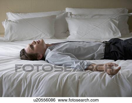 A man laying on a bed View Large Photo Image Stock Photograph - A man laying on a bed. Fotosearch