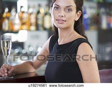 Stock Image - A woman drinking champagne in a bar. Fotosearch