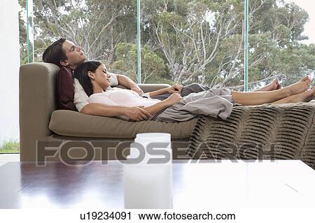 A young couple laying on a sofa View Large Photo Image Stock Image - A young couple laying on a sofa. Fotosearch