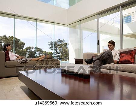 Stock Photo - A young couple sitting in a living room. Fotosearch
