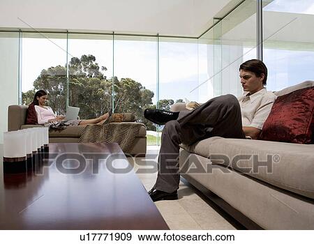 Stock Photo - A young couple sitting in a living room. Fotosearch