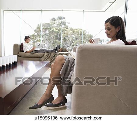 A young couple sitting in a living room View Large Photo Image Stock Photograph - A young couple sitting in a living room. Fotosearch