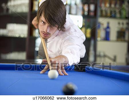 Stock Image - A businessman playing pool in a bar. Fotosearch