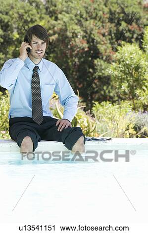 A businessman sitting by a swimming pool talking on a mobile phone View Large Photo Image Stock Image - A businessman sitting by a swimming pool talking on a mobile phone. Fotosearch