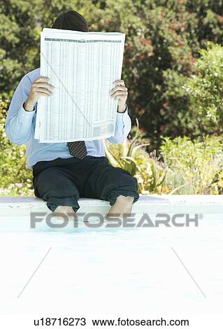 A businessman sitting by a swimming pool reading the paper View Large Photo Image Stock Image - A businessman sitting by a swimming pool reading the paper. Fotosearch