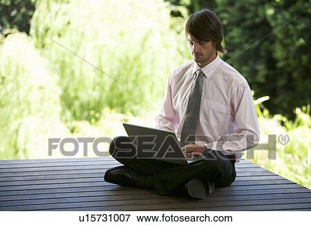 A businessman using a laptop in a garden View Large Photo Image Stock Photo - A businessman using a laptop in a garden. Fotosearch