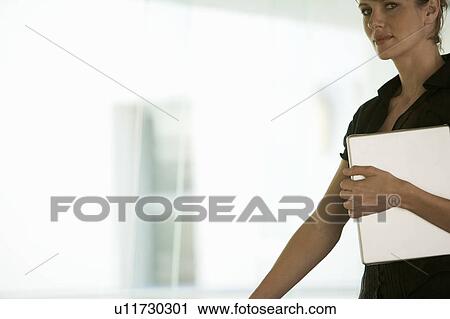 Stock Image - A businesswoman carrying a laptop. Fotosearch
