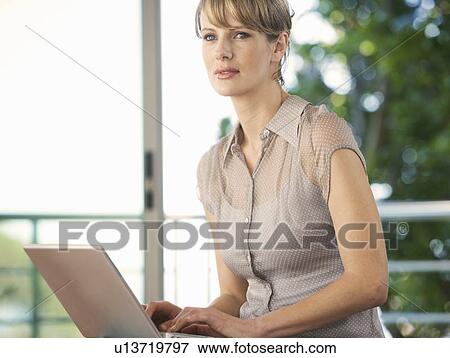 A businesswoman sitting in a gym using a laptop View Large Photo Image Stock Photo - A businesswoman sitting in a gym using a laptop. Fotosearch