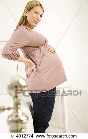 A pregnant woman holding her back View Large Photo Image Picture - A pregnant woman holding her back. Fotosearch