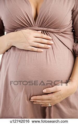 A pregnant woman holding her bump View Large Photo Image Stock Photograph - A pregnant woman holding her bump. Fotosearch