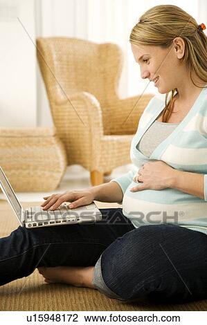 Stock Image - A pregnant woman using a laptop. Fotosearch