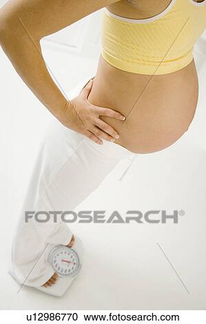 A pregnant woman weighing herself View Large Photo Image Stock Image - A pregnant woman weighing herself. Fotosearch