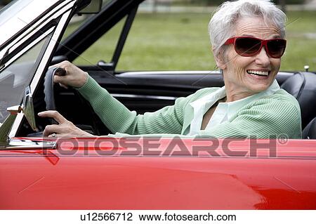 Stock Image - A senior woman driving a sports car. Fotosearch