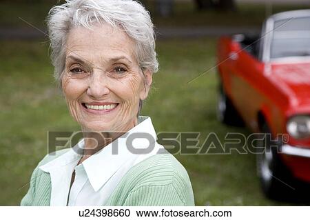 A senior woman standing by a sports car View Large Photo Image Stock Image - A senior woman standing by a sports car. Fotosearch