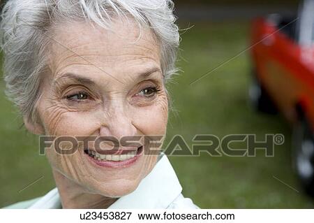 Stock Photo - A senior woman standing by a sports car. Fotosearch
