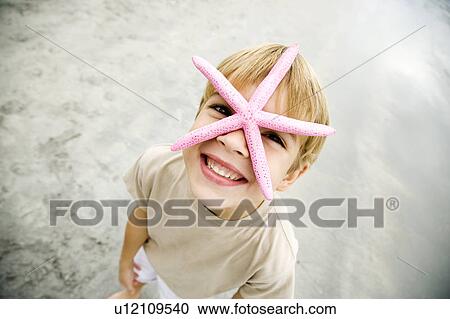 Stock Image - A young boy holding a starfish. Fotosearch