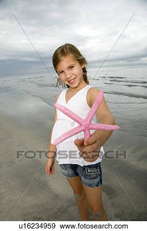 Stock Photo - A young girl holding a starfish. Fotosearch
