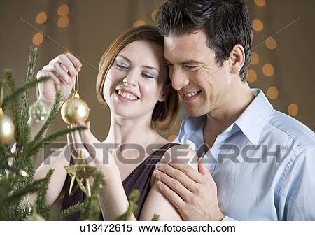 A couple hanging decorations on a Christmas tree View Large Photo Image Stock Photography - A couple hanging decorations on a Christmas tree. Fotosearch