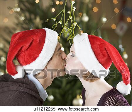 A couple kissing beneath the mistletoe View Large Photo Image Stock Photography - A couple kissing beneath the mistletoe. Fotosearch