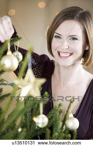 A woman decorating a Christmas tree View Large Photo Image Stock Image - A woman decorating a Christmas tree. Fotosearch
