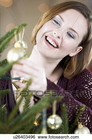 A woman decorating a Christmas tree View Large Photo Image Stock Photograph - A woman decorating a Christmas tree. Fotosearch
