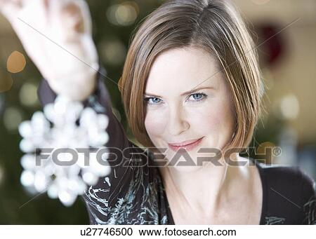 Stock Image - A woman holding a Christmas decoration. Fotosearch