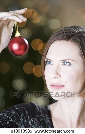Stock Photography - A woman holding a Christmas decoration. Fotosearch