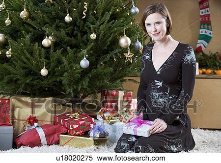 A woman putting presents under the Christmas tree View Large Photo Image Stock Photography - A woman putting presents under the Christmas tree. Fotosearch
