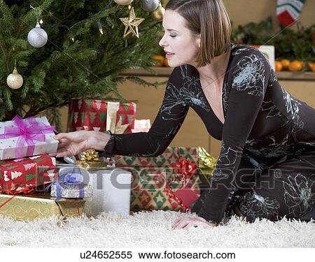 A woman putting presents under the Christmas tree View Large Photo Image Stock Photography - A woman putting presents under the Christmas tree. Fotosearch