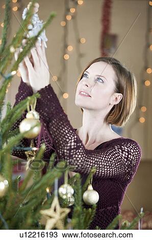 A woman putting the fairy on top of the Christmas tree View Large Photo Image Stock Image - A woman putting the fairy on top of the Christmas tree. Fotosearch