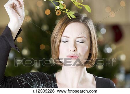 Stock Photograph - A woman waiting for kiss under the mistletoe. Fotosearch