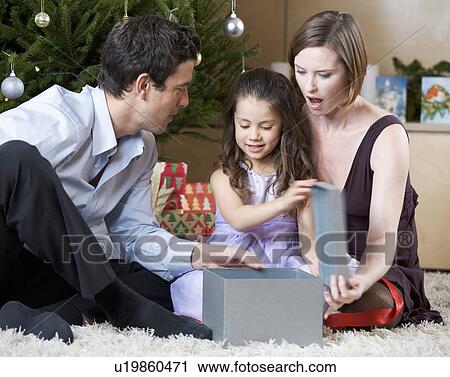 A couple and their young daughter opening Christmas presents View Large Photo Image Stock Image - A couple and their young daughter opening Christmas presents. Fotosearch