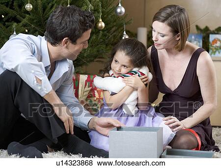 Stock Photo - A couple and their young daughter opening Christmas presents. Fotosearch