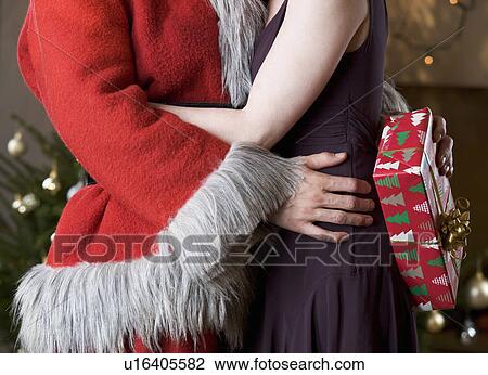 A couple at Christmas with the man wearing a Santa Claus Costume View Large Photo Image Stock Image - A couple at Christmas with the man wearing a Santa Claus Costume. Fotosearch