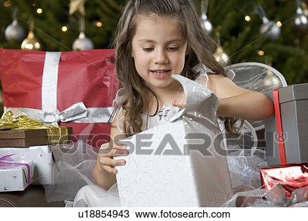 Stock Image - A young girl dressed as a fairy opening a Christmas present. Fotosearch
