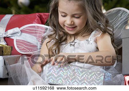 Stock Photo - A young girl dressed as a fairy opening a Christmas present. Fotosearch