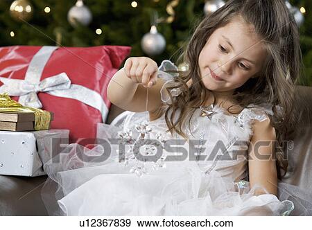 Stock Photo - A young girl dressed as a fairy opening a Christmas present. Fotosearch