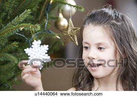 A young girl putting a decoration on a Christmas tree View Large Photo Image Picture - A young girl putting a decoration on a Christmas tree. Fotosearch