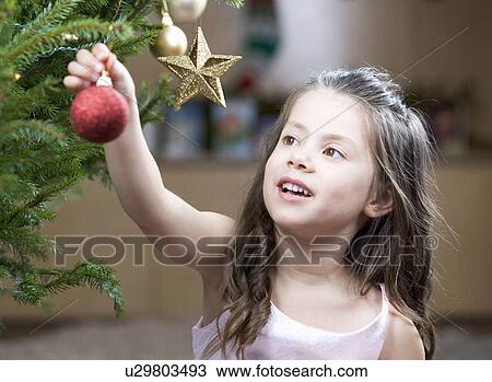 A young girl putting a decoration on a Christmas tree View Large Photo Image Stock Image - A young girl putting a decoration on a Christmas tree. Fotosearch
