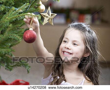 A young girl putting a decoration on a Christmas tree View Large Photo Image Stock Photo - A young girl putting a decoration on a Christmas tree. Fotosearch