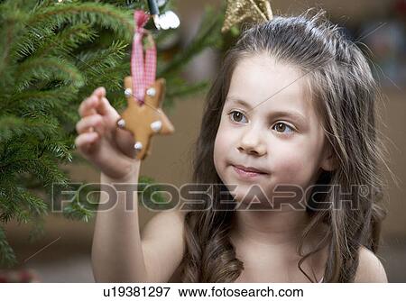 A young girl putting a decoration on a Christmas tree View Large Photo Image Stock Photo - A young girl putting a decoration on a Christmas tree. Fotosearch