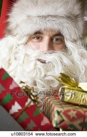 Picture - Father christmas / santa Claus holding a pile of presents. Fotosearch