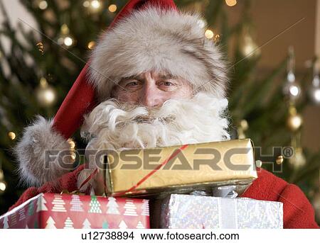 Father christmas / santa Claus holding a pile of presents View Large Photo Image Picture - Father christmas / santa Claus holding a pile of presents. Fotosearch
