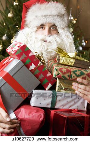 Father christmas / santa Claus holding a pile of presents View Large Photo Image Stock Photo - Father christmas / santa Claus holding a pile of presents. Fotosearch